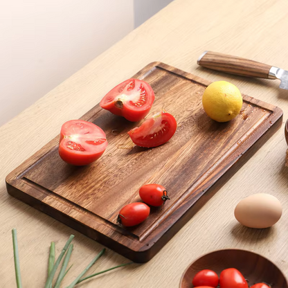 Wooden cutting board with sliced tomatoes, a lemon, and an egg on a light wooden surface.