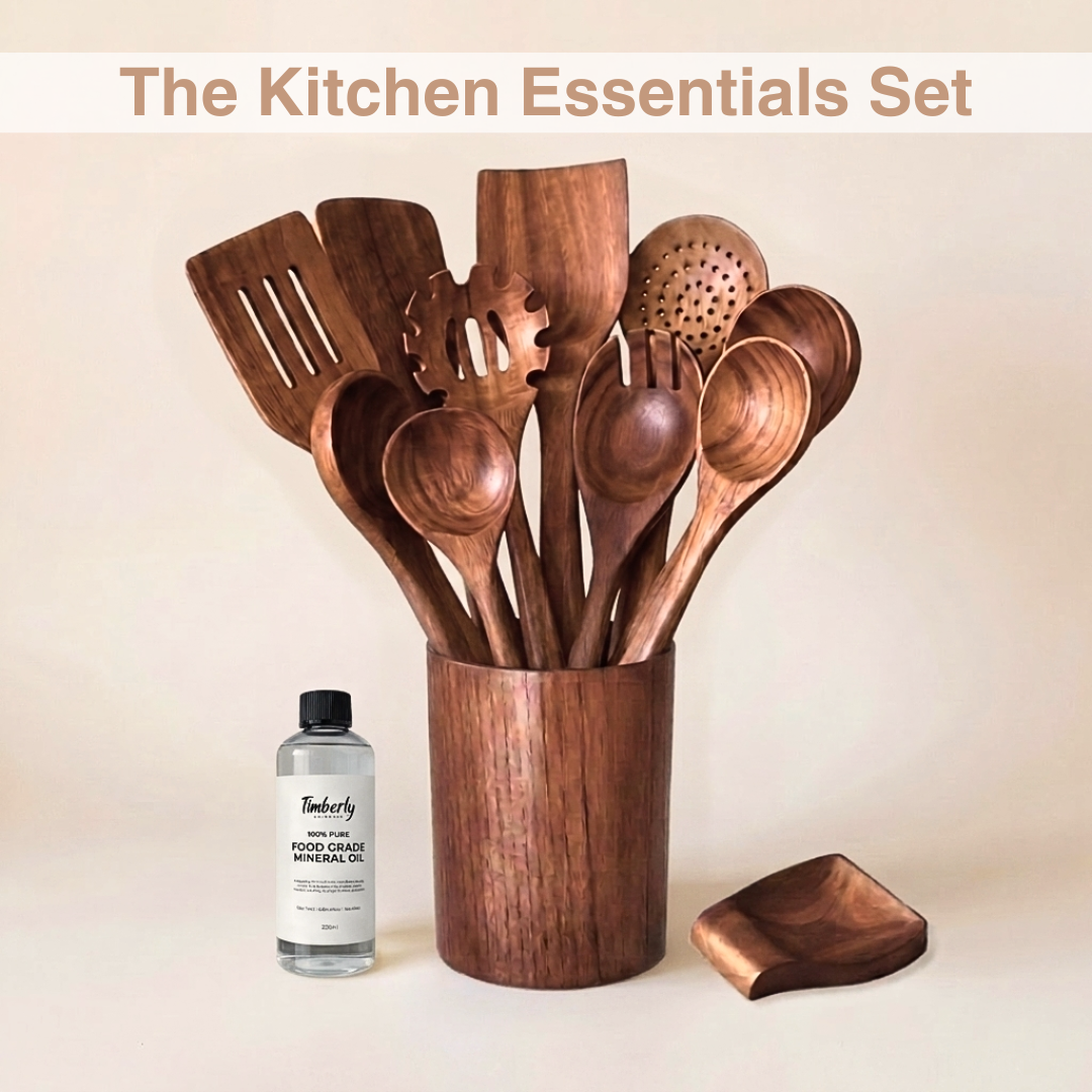 A wooden kitchen utensil set displayed in a matching wooden holder, with a small bottle of Timberly hand-oiled wood furniture oil placed beside it on a warm beige background. Text at the top reads 'The Kitchen Essentials Set'.